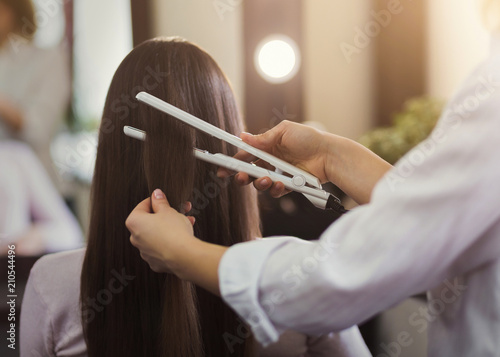 Hairdresser straightening long brown hair photo