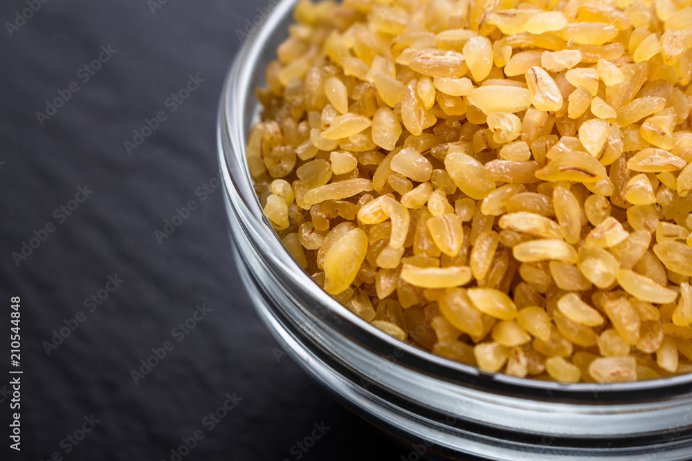 raw bulgur on a dark stone background raw bulgur on a dark stone background