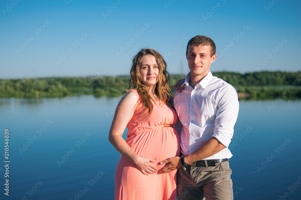 Young happy pregnant couple resting outdoors in summer Young happy pregnant couple resting outdoors in summer