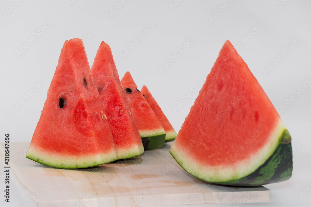 Sliced red watermelon on a wooden cutting board. Isolated. Sliced red watermelon on a wooden cutting board. Isolated.