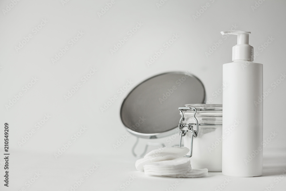 Beautiful minimalist conceptual all white composition - cotton pads, transparent jar and plastic bottle with pump Beautiful minimalist conceptual all white composition - cotton pads, transparent jar and plastic bottle with pump