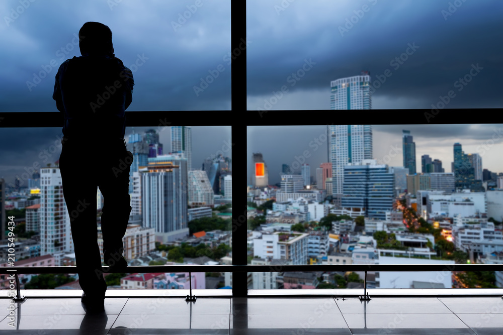 Man looking through window at cityscape stock photo - OFFSET