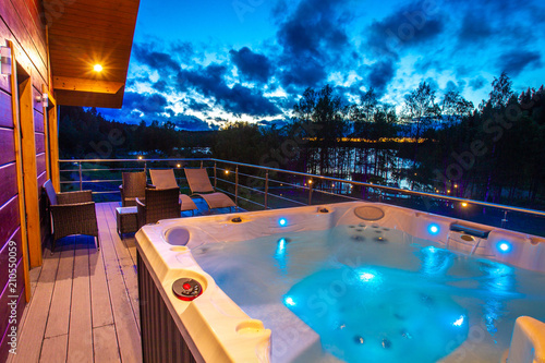 View from the house to the pool. Hydromassage. Pool on the balcony of the cottage. Jacuzzi on the background of the evening sky. Cottage with spa complex. House with pool. photo