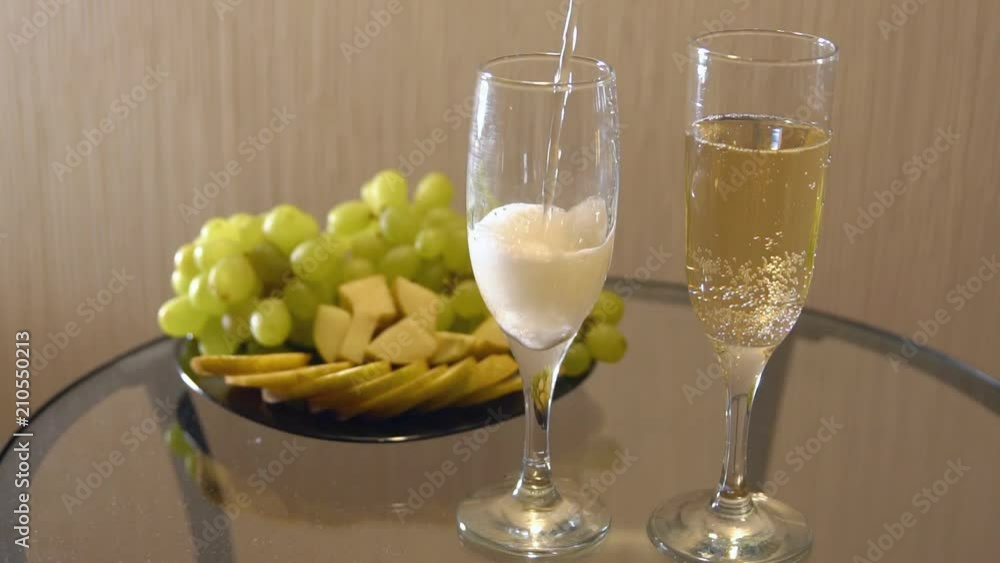 Champagne in glasses and a plate of fruit on the table, slow motion Champagne in glasses and a plate of fruit on the table, slow motion