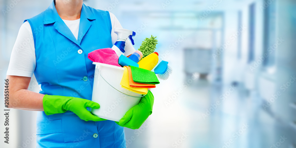Female cleaner holding a bucket with cleaning supplies - obrazy, fototapety, plakaty 