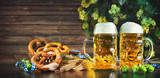 Bavarian beer with soft pretzels, wheat and hop on rustic wooden table