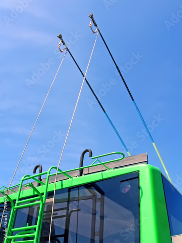 green trolleybus metal bars with stairs on blue sky with white clouds, power outage, modern urban transportation