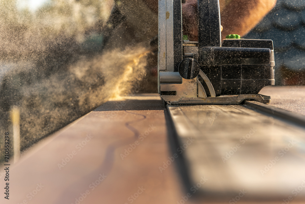 A carpenter cuts a kitchen worktop with a circular saw. He uses an