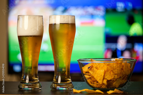 beer glasses and chips in front of tv - watching world cup football at home - soccer supporters