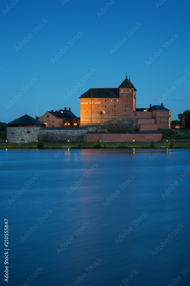 Beautiful view of lit 13th century Häme Castle and lake Vanajavesi in Hämeenlinna, Finland, in the evening.