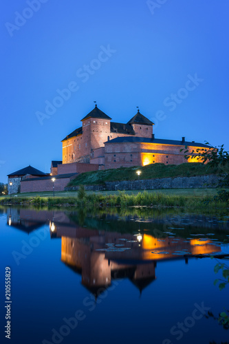 Beautiful view of lit 13th century Häme Castle and its reflections on lake Vanajavesi in Hämeenlinna, Finland, at night.