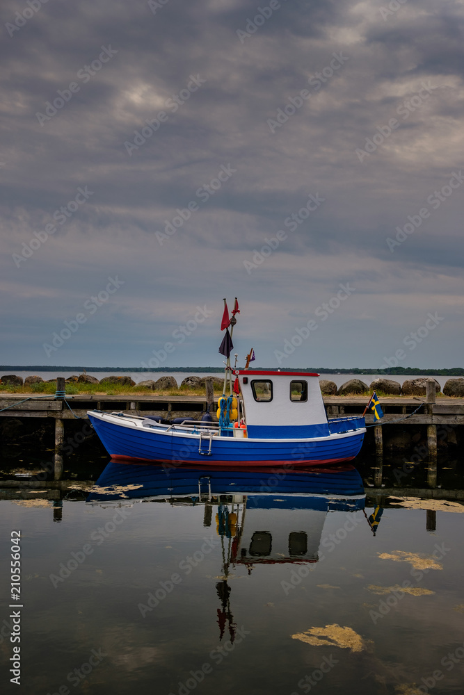 Fototapeta premium Blue and whithe fishing boat with reflections in the water