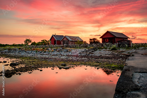 Red fishing huts during sunrise and stones on the beach