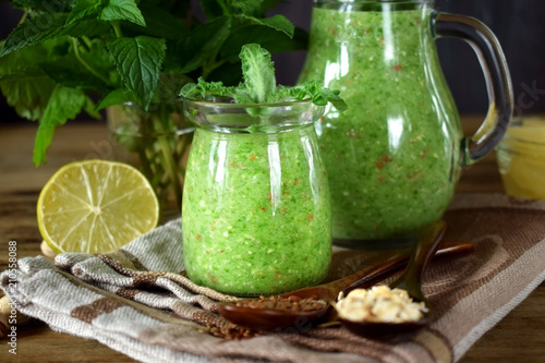 Green smoothie in a glass jar and jug topped with mint