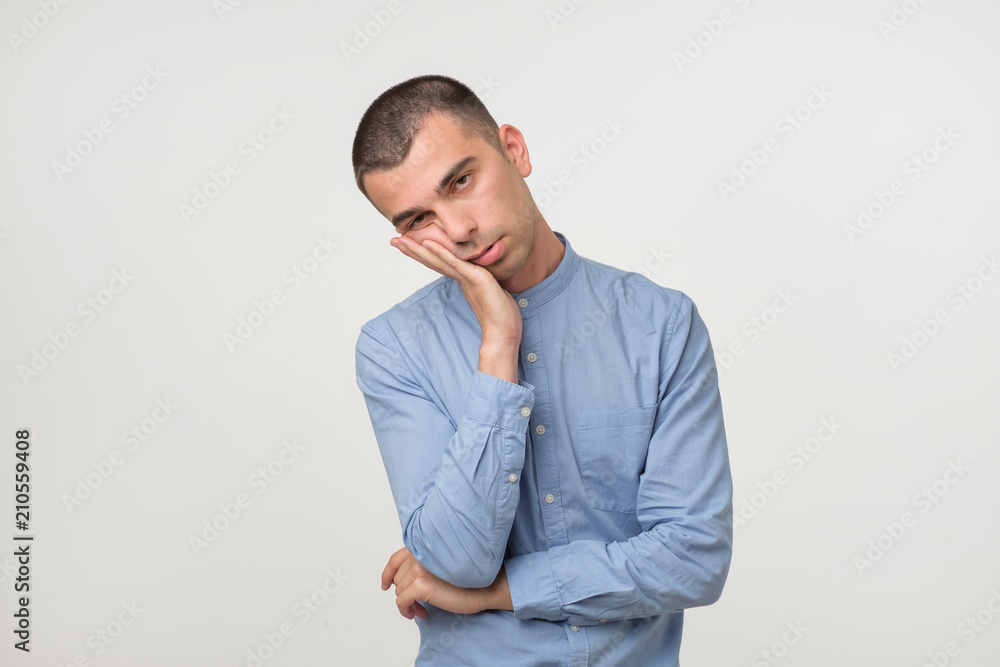 Young man wearing a blue outfit putting his palms like a pillow. Looking sleepy and tired. Young man wearing a blue outfit putting his palms like a pillow. Looking sleepy and tired.