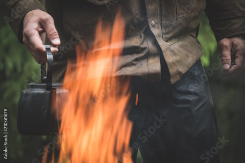 Man holding a coffee pot over a flame
