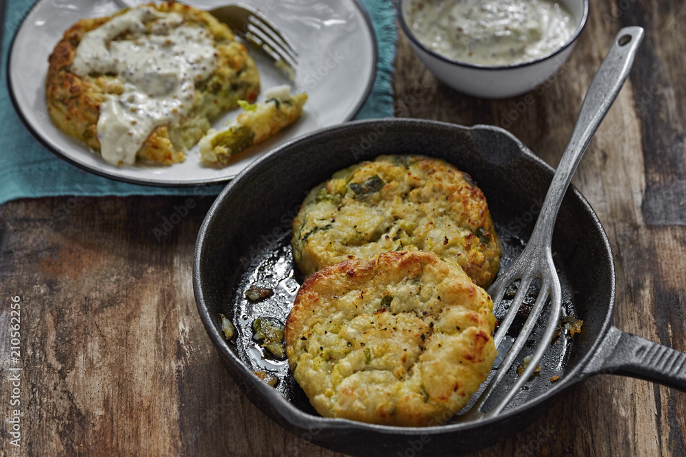 Haddock cabbage potato cakes with mustard sauce on wooden table 