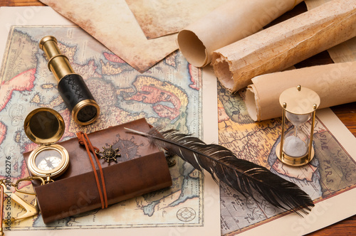 Planning a trip: quill pen, old rolled papers and maps with vintage items