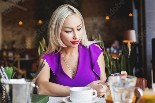 Smiling female model woman with smartphone in restaurant