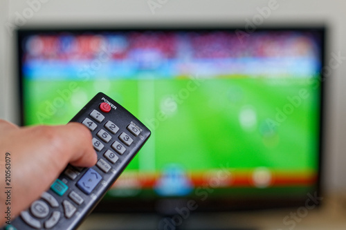 Man's hand holding remote during watching match on tv