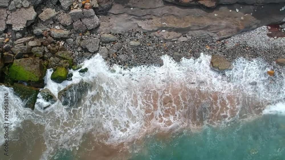 Aerial top view of sea waves hitting rocks on the beach with turquoise sea water. Amazing rock cliff seascape in the Portuguese coastline. Aerial top view of sea waves hitting rocks on the beach with turquoise sea water. Amazing rock cliff seascape in the Portuguese coastline.