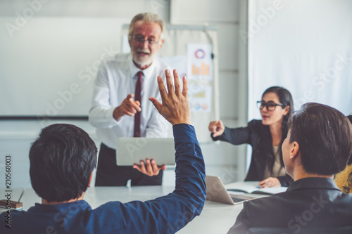 Businessman raising hand for asking speaker for question and answer concept in meeting room of diversity business people