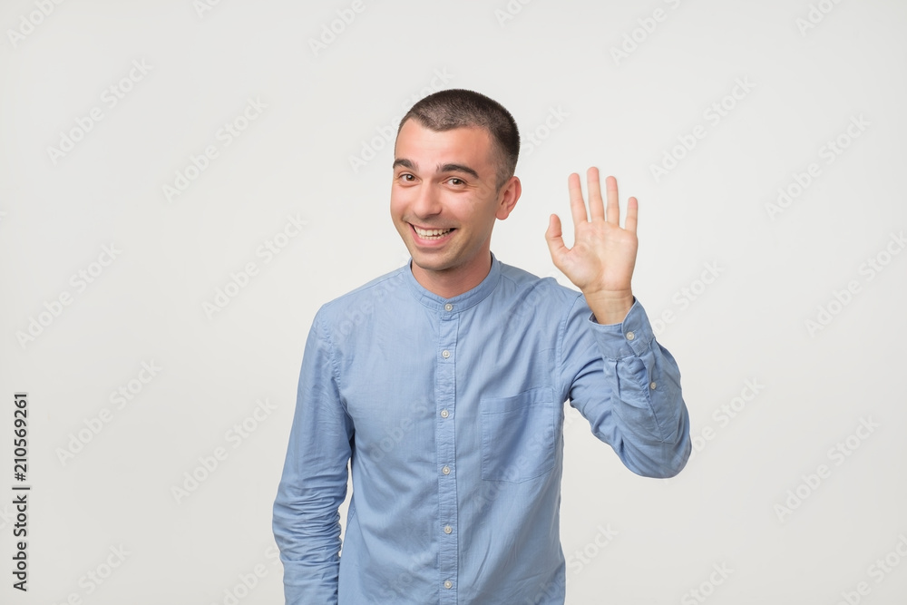 Man with blue shirt saying hello, waving a hand Man with blue shirt saying hello, waving a hand