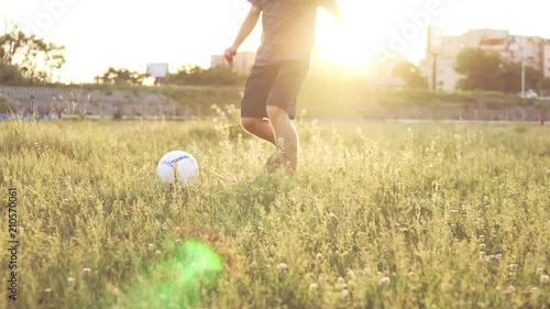 Slide slow motion a defocusing in focus on the football player's figures giving a pass ball. A teenager is playing on an abandoned football field at sunset on a sunny day in the summer. Football field