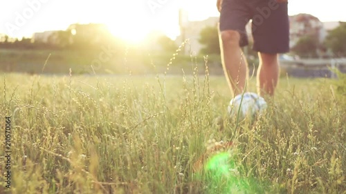 Slide slow motion a defocusing in focus on the football player's figures giving a pass ball. A teenager is playing on an abandoned football field at sunset on a sunny day in the summer. Football field