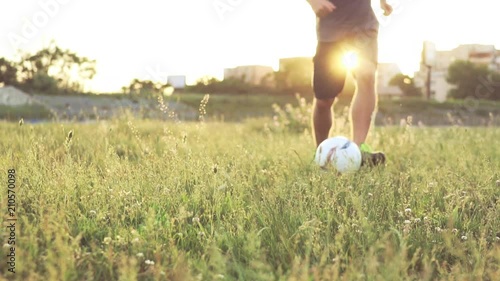 Slide slow motion a defocusing in focus on the football player's figures giving a pass ball. A teenager is playing on an abandoned football field at sunset on a sunny day in the summer. Football field