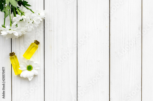 Cosmetics for skin care with chamomile. Chamomile oil on white wooden background top view copy space