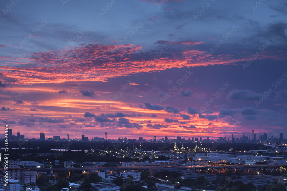 Obraz premium A night landscape view of city and Oil refinery industry under colorful sky at sunset time