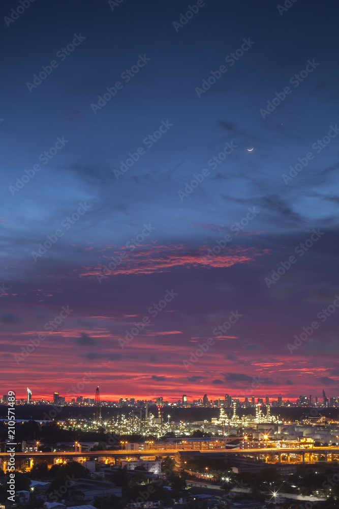 Fototapeta premium A night landscape view of city and Oil refinery industry under colorful sky at sunset time