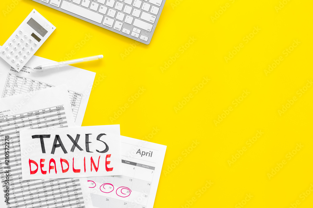 Taxes deadline words on office work desk with calendar and bills on yellow background top view copy space. Circled dates Taxes deadline words on office work desk with calendar and bills on yellow background top view copy space. Circled dates