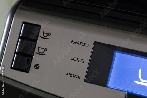 The panel of the automatic coffee machine with the inscriptions of drinks and the blue display