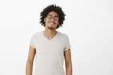Good-looking confident and carefree man with afro haircut and moustache in trendy glasses with black rim, smiling joyfully and pleased while bragging about new app he made for smartphones