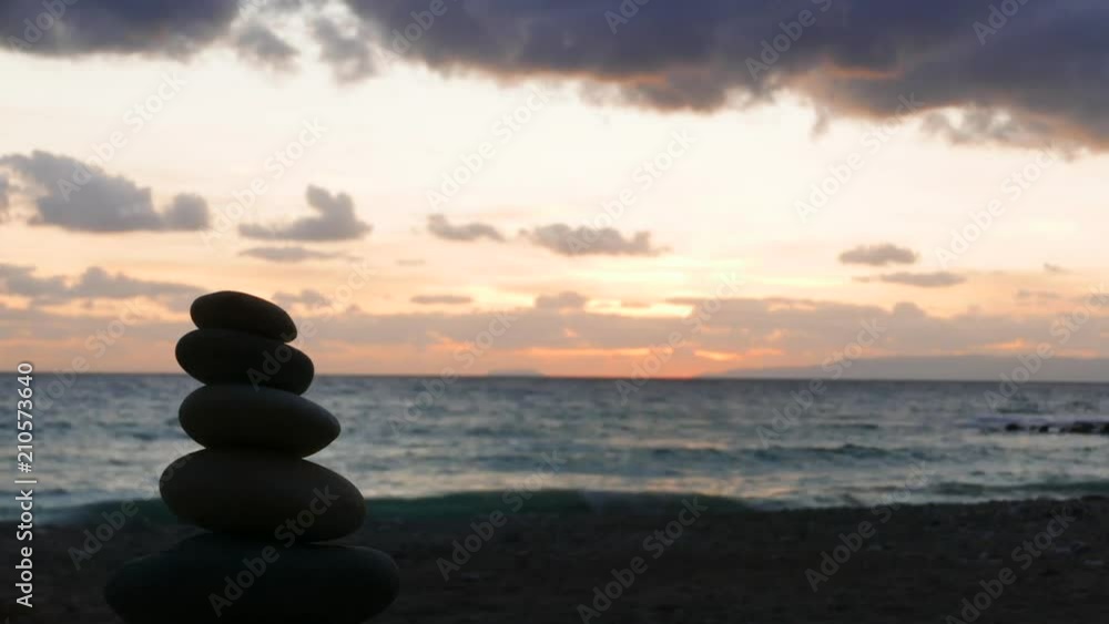 Stone stack on beach and dramatic sunset over sea surface with dark stormy rainy clouds, Greece Peloponnese, time lapse Stone stack on beach and dramatic sunset over sea surface with dark stormy rainy clouds, Greece Peloponnese, time lapse