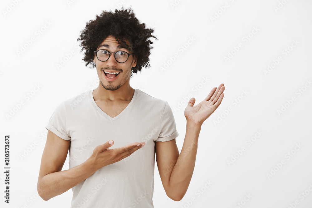 Portrait of happy excited attractive hispanic male hipster with moustache and afro haircut in glasses, pointing right with palms, showing something amazing and amusing, discussing interesting object Portrait of happy excited attractive hispanic male hipster with moustache and afro haircut in glasses, pointing right with palms, showing something amazing and amusing, discussing interesting object