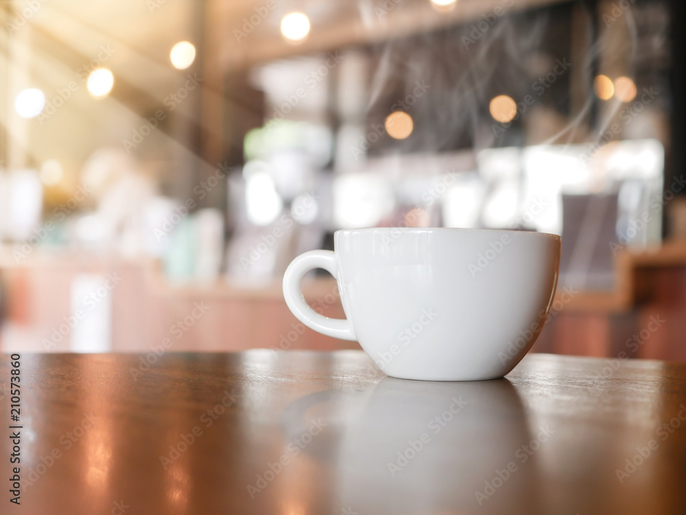Fototapeta premium A cup of espresso coffee on wooden table in the background of cafeteria