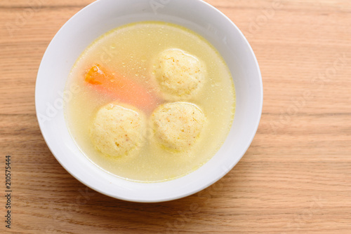 Traditional matzoh ball (kneidlach) soup.White bowl with authentic matzo ball chicken taste hot soup ( bouillon ) tradition Jewish food for Passover and every day.