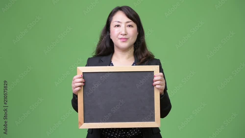 Mature beautiful Asian businesswoman showing blackboard Mature beautiful Asian businesswoman showing blackboard