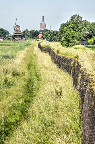 Dike, reinforced with a brick wall, that seperates the floodlands and the polder near Hasselt, The Netherlands photo