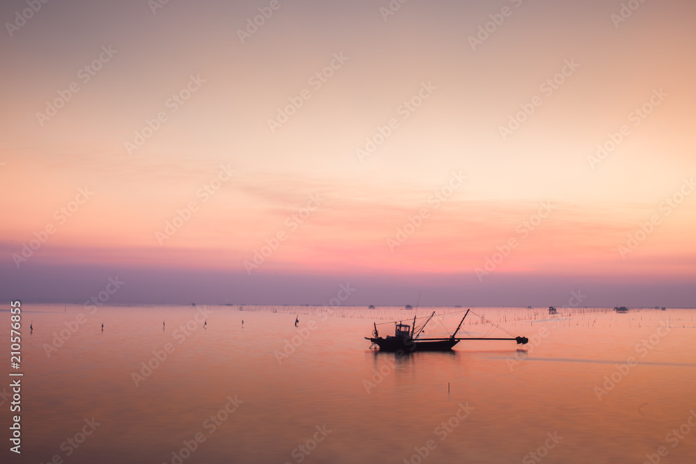 A colorful of sunset is reflect above of sea with long boat