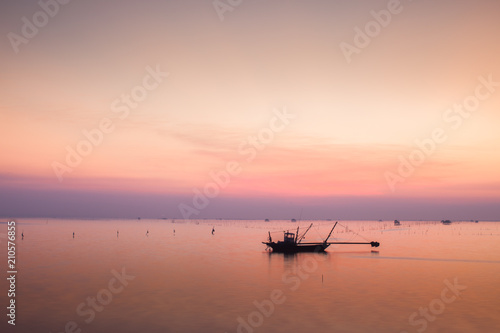 A colorful of sunset is reflect above of sea with long boat