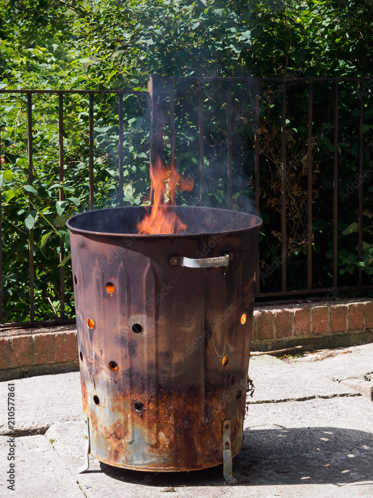 Destruction of garbage by means of burning in a Garden incinerator bin.  Cause smoke, which air pollution. Not helping the environment. Stock Photo  | Adobe Stock