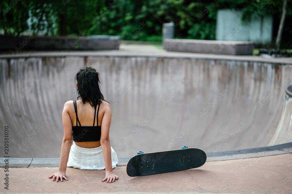 Φωτογραφία An image of a young and pretty Chinese skater girl sitting at the lip of a skating bowl