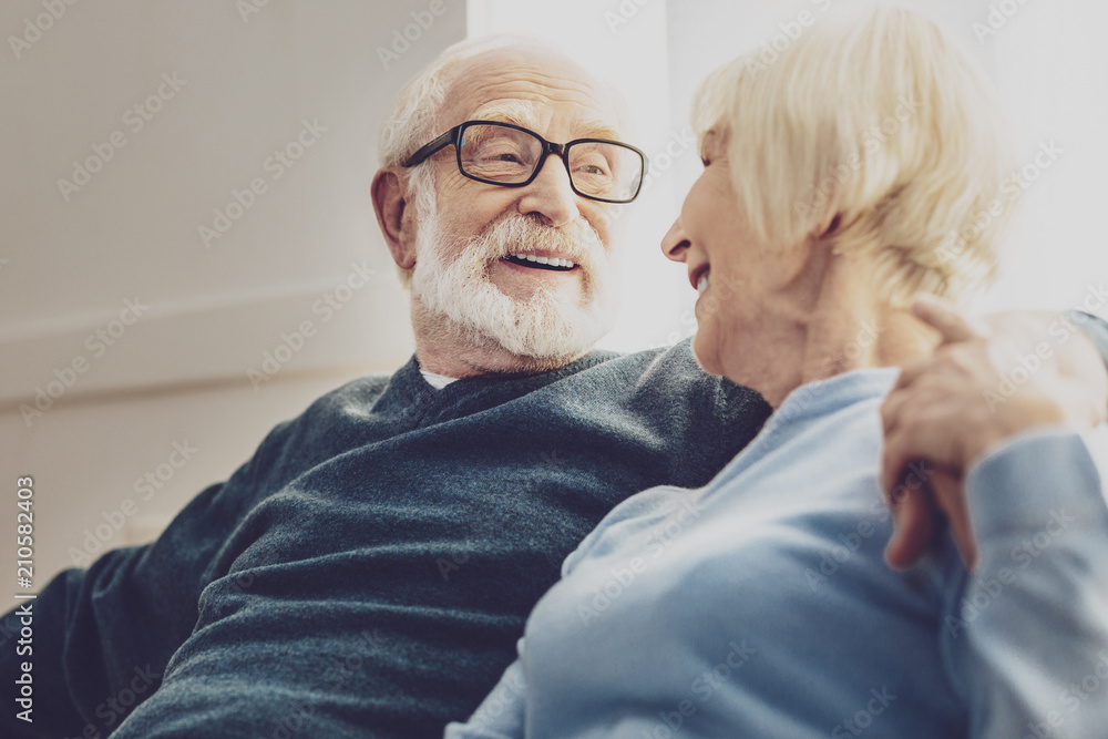Joyful mood. Nice elderly man hugging his woman while having a conversation with her Joyful mood. Nice elderly man hugging his woman while having a conversation with her