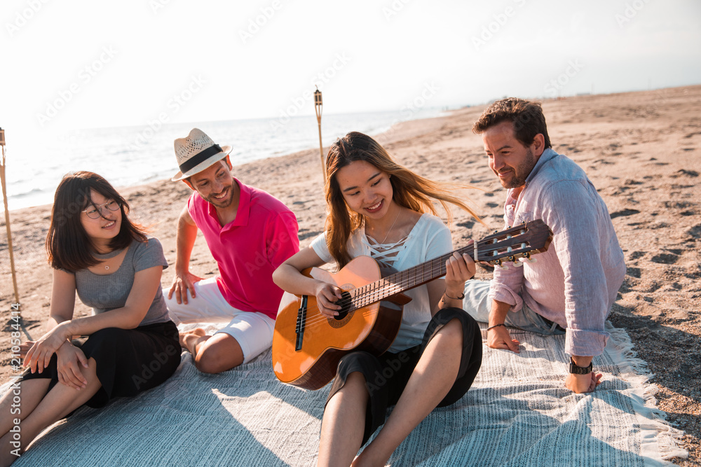 Obraz premium Multicultural group of friends partying on the beach - Young people celebrating during summer vacation, summertime and holidays concepts