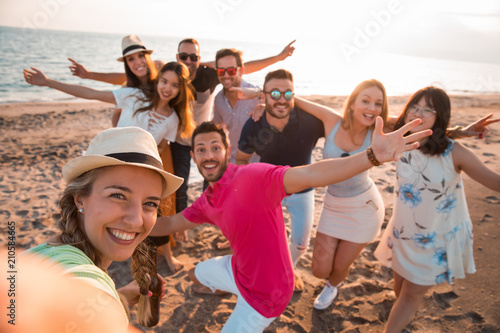 Happy multiracial young people are making a selfie at the beach while they are in a summer party. Friends and holiday concept photo