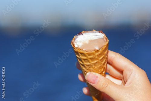 Ice cream cone, chocolate ice cream on blurred background, milk dessert on summer vacation, blank for designer with hand, copy space, milk product